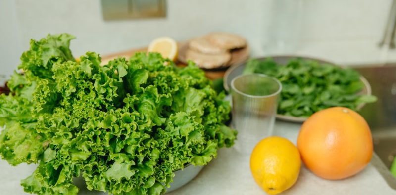 A vibrant display of fresh green lettuce and citrus fruits on a kitchen table.